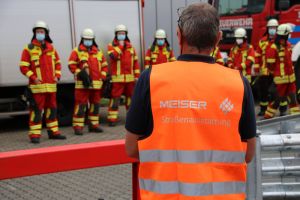 Im Hintergrund die Feuerwehr Schmelz auf dem Gelände von Meiser Straßenausstattung. Im Vordergrund ein Mitarbeiter der Meiser Straßenausstattung.
