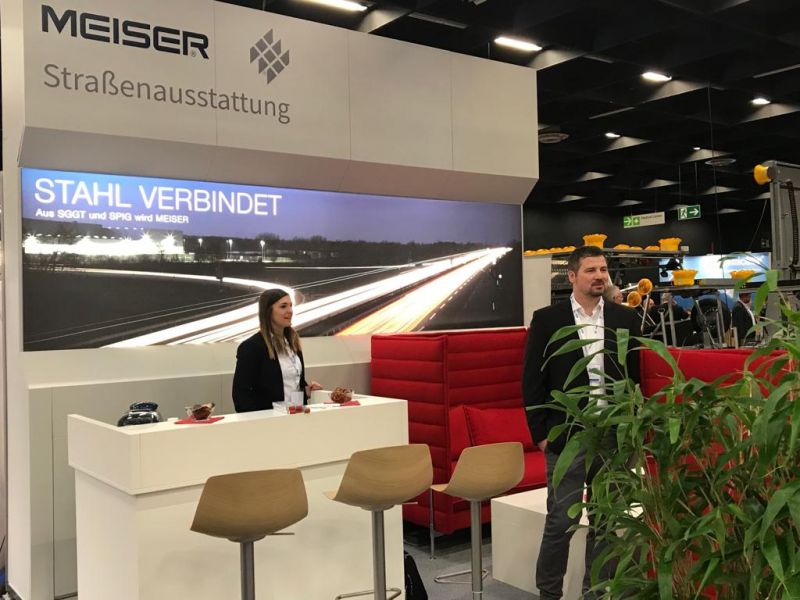 Mitarbeitende des Leitplanken Herstellers MEISER Straßenausstattung an einem Stand mit großem Meiser Logo, einem Foto einer Leitplanke  auf der DeuSat (Deutscher Straßenausstattertag).